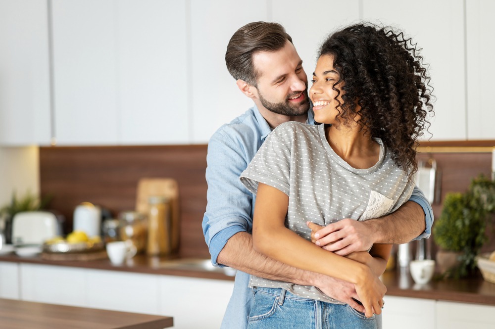 a man and woman hugging in a kitchen.