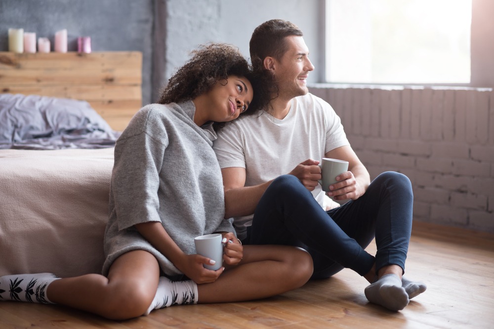 A man and woman sitting on the floor with a cup of coffee