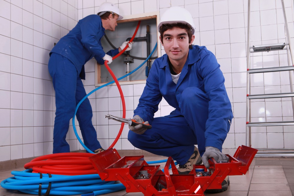 Two man in a blue dress working on a pipe